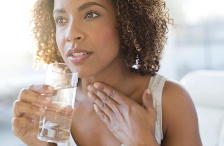 Young woman drinking water with hand on throat have difficulty swallowing