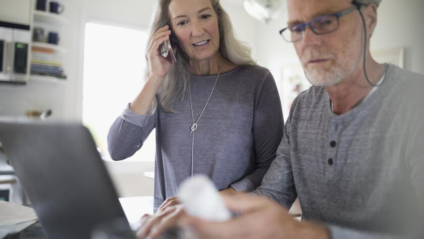 Middle aged Caucasian couple looking at medicine bottle while on phone