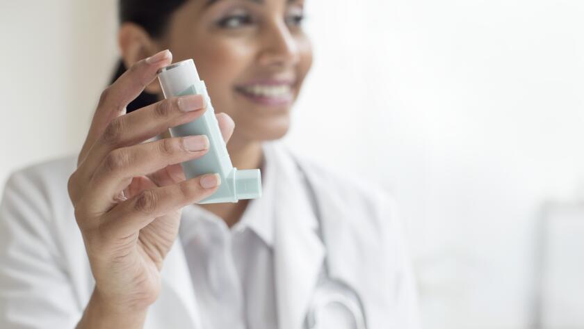 doctor holding up inhaler and smiling