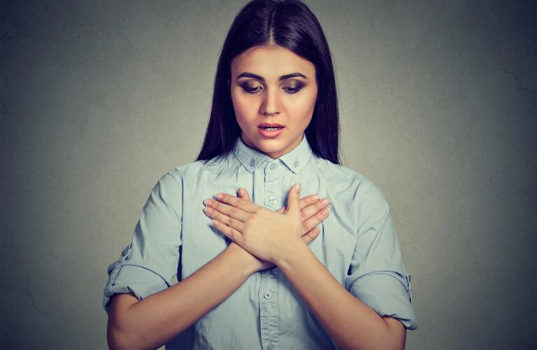 young woman with asthma attack or respiratory problem holding hands to chest