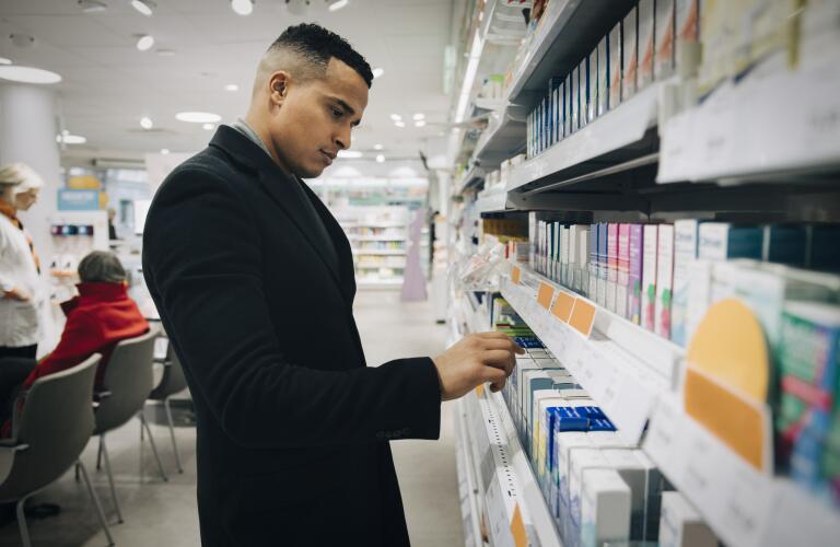 Young Hispanic man looking at shelf of pharmacy