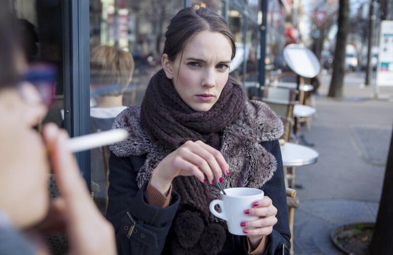 Young Caucasian woman giving serious look to friend smoking cigarette