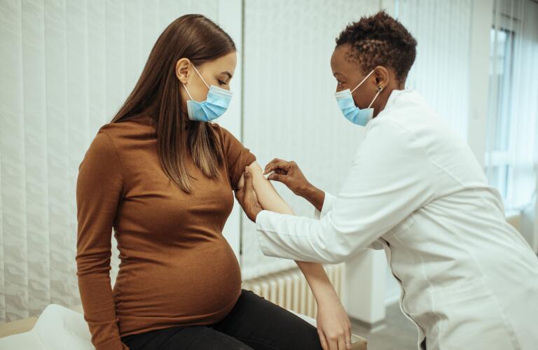 African American female doctor preparing a pregnant woman for vaccination
