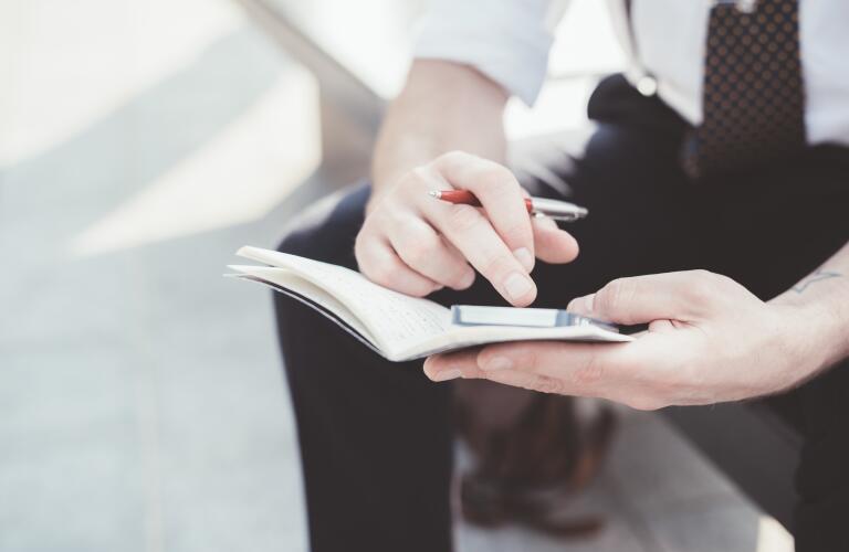 man-looking-at-smartphone-and-planner
