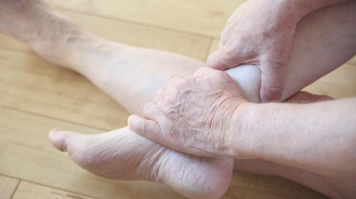 Caucasian man holding left foot while sitting on floor