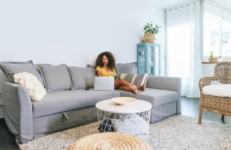 young woman with laptop on sofa with feet up