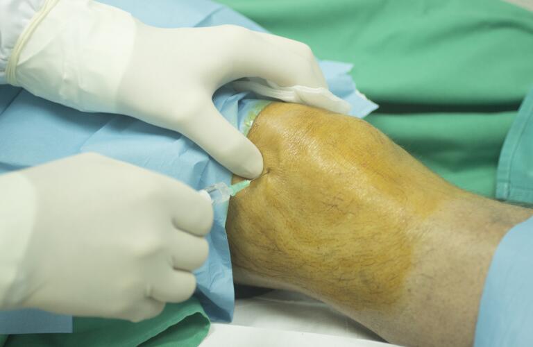 nurse giving knee injection to male patient, joint procedure