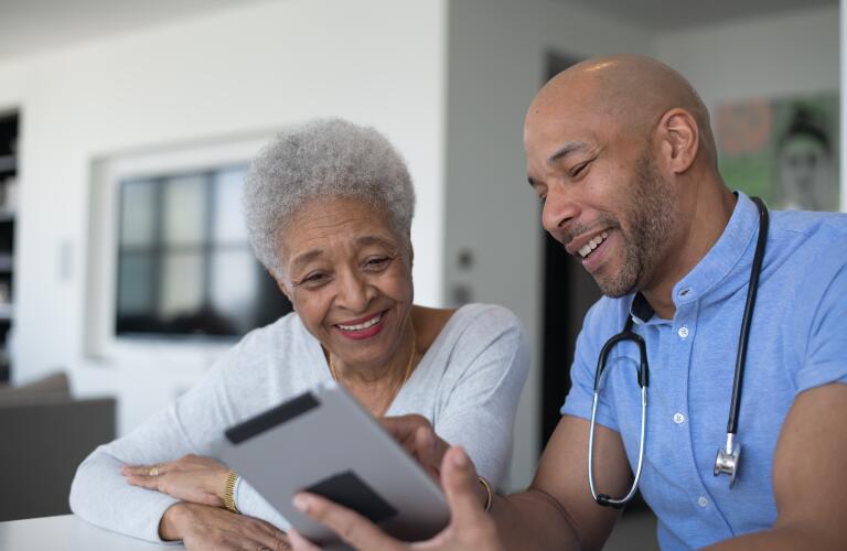 male doctor consulting with female African American patient over tablet