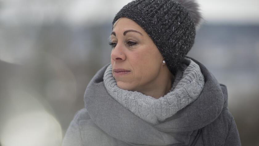 Middle age Caucasian woman in winter coat and hat outside looking sad
