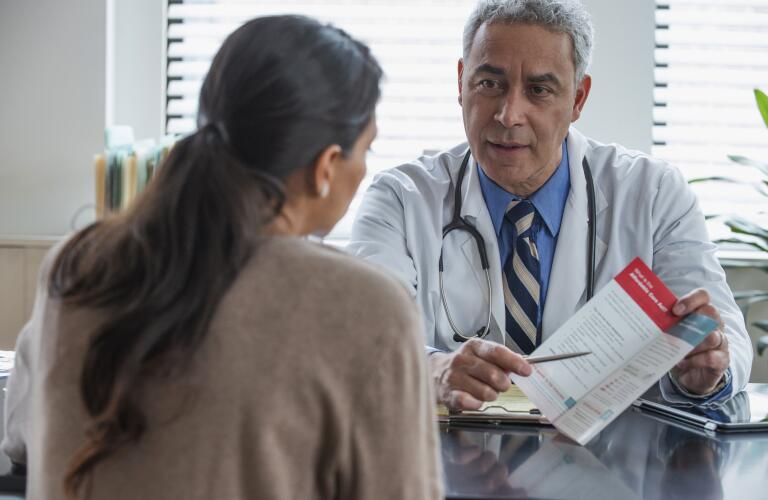 Hispanic doctor explaining pamphlet to client in office