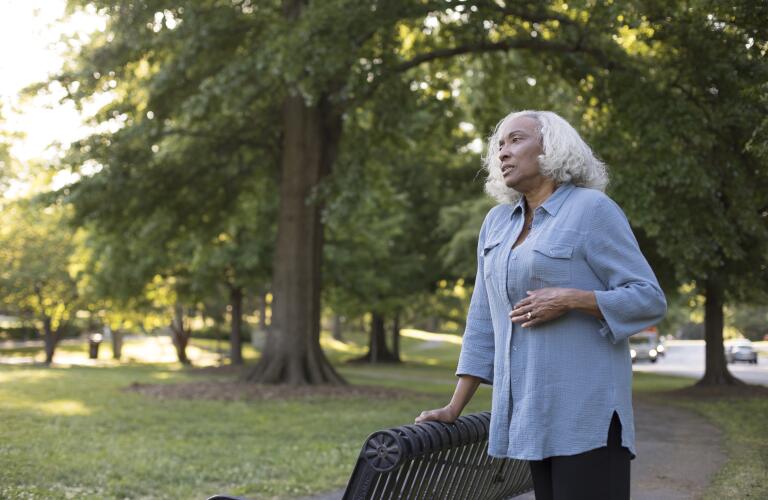 Senior African American woman in park with hand on stomach