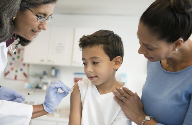 Young Hispanic boy getting vaccination or flu shot from pediatrician or nurse