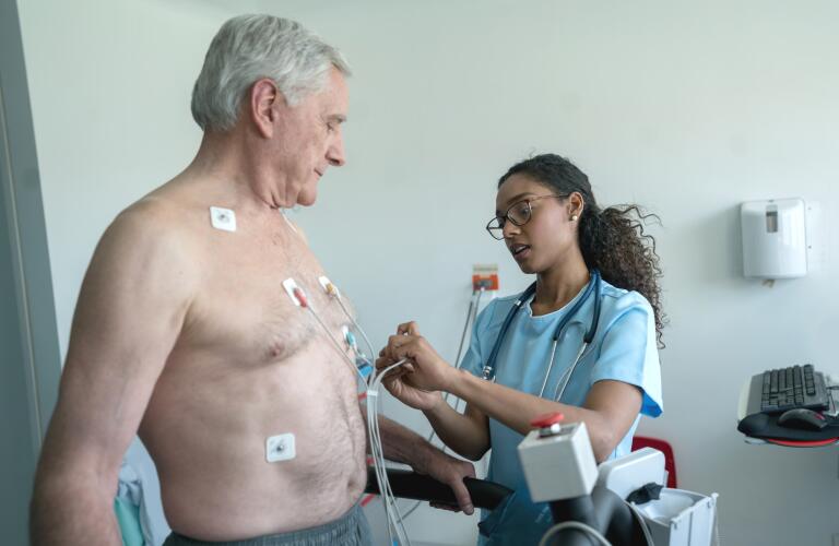 Nurse putting electrones on a senior patient who is ready for a stress test on a treadmill