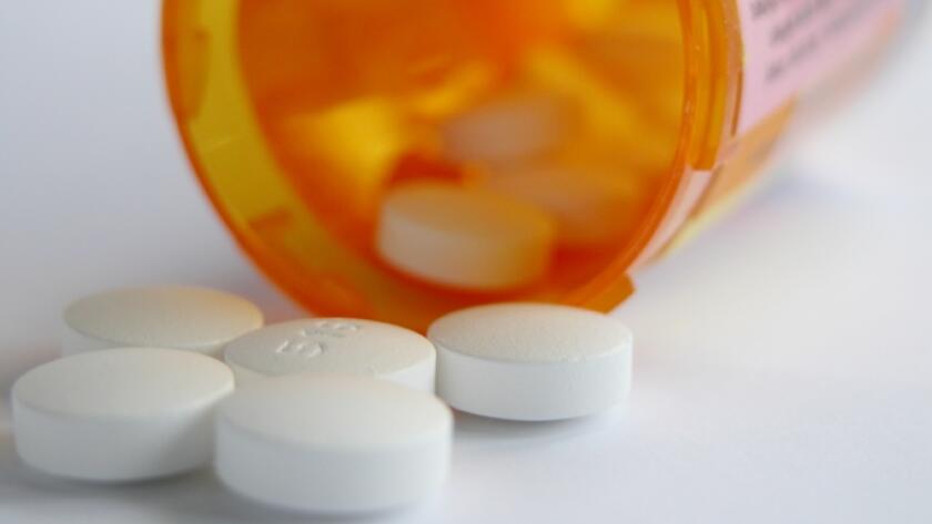 White pills spill from medicine bottle