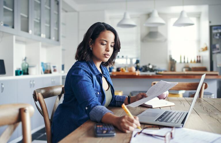 Young Hispanic woman working on laptop in home kitchen