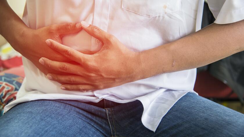 man with abdominal pain clutching stomach with hands