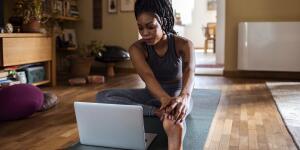 Woman learning yoga pose on floor with laptop
