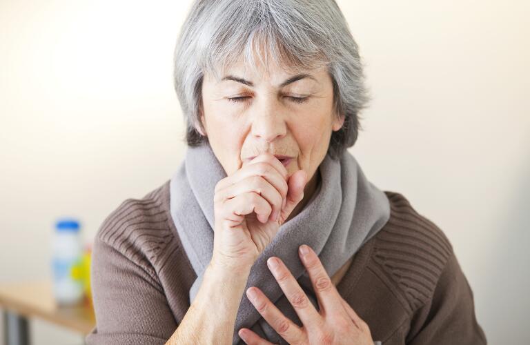 senior woman coughing in hand