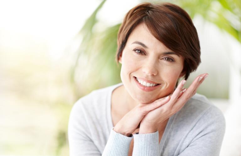Smiling woman with face in hands