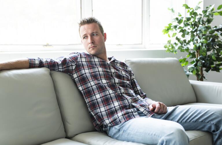 depressed male sitting on couch looking away