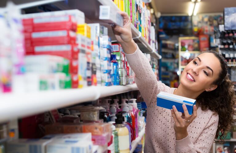 woman choosing toothpaste in grocery aisle