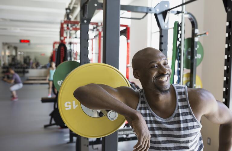 Enthusiastic man leaning on barbell at gym