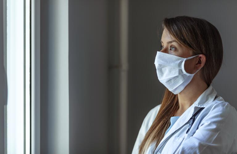 Female doctor in mask looking out window