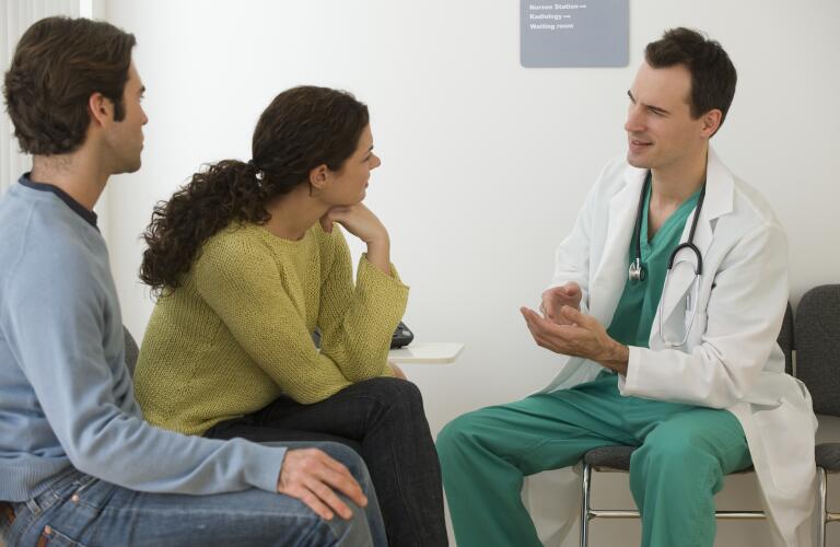 Male doctor talking to couple in waiting room