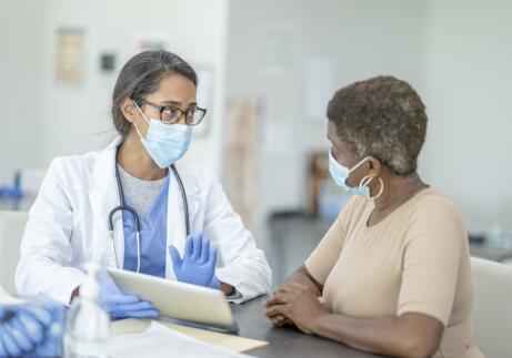 female doctor with digital tablet talking to female patient in medical exam