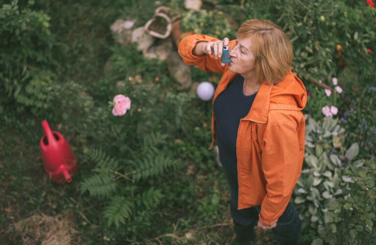 senior woman using inhaler in her garden