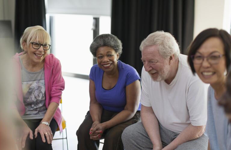 group of smiling seniors sitting in circle during support group session