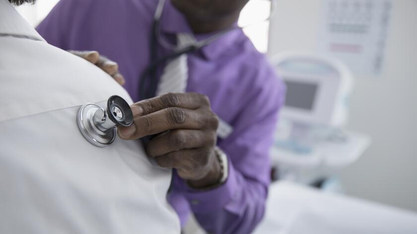 doctor placing stethoscope on patient's back