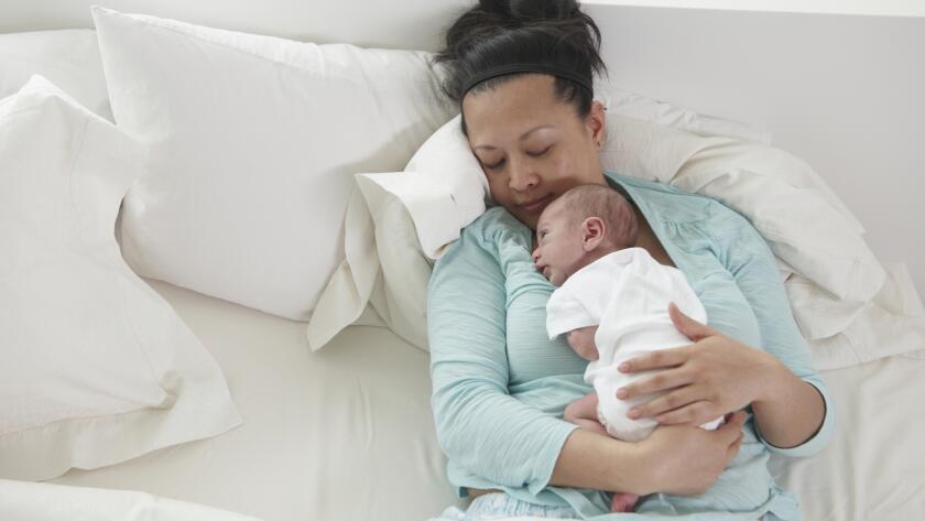 Chinese mother holding sleeping newborn