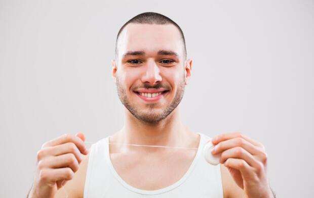 smiling man holding up dental floss smiling man holding up dental floss