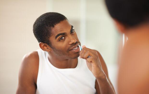 man brushing teeth against black background