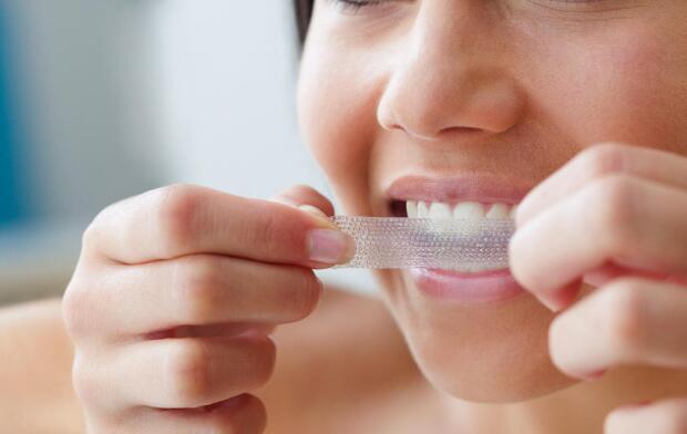 woman using teeth whitening strip