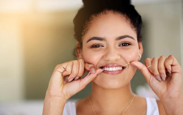 smiling woman flossing teeth