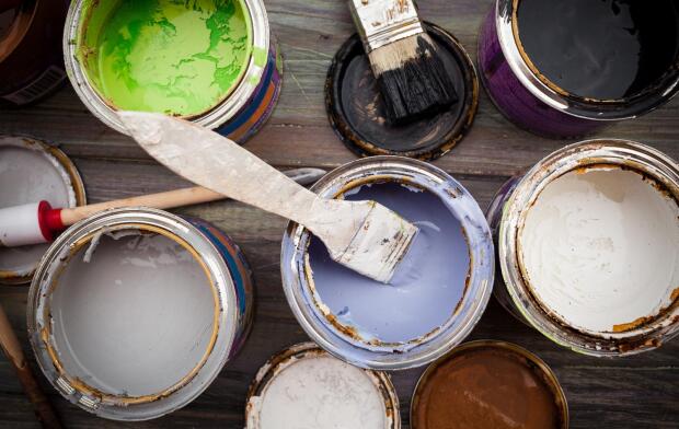 group of colorful open paint cans with brush