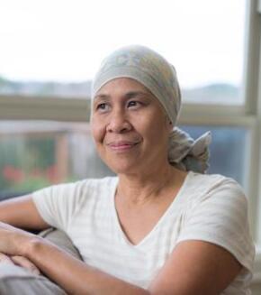 cancer patient sitting by window in head wrap