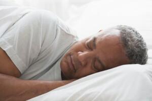 portrait of senior African American male sleeping in bed on side