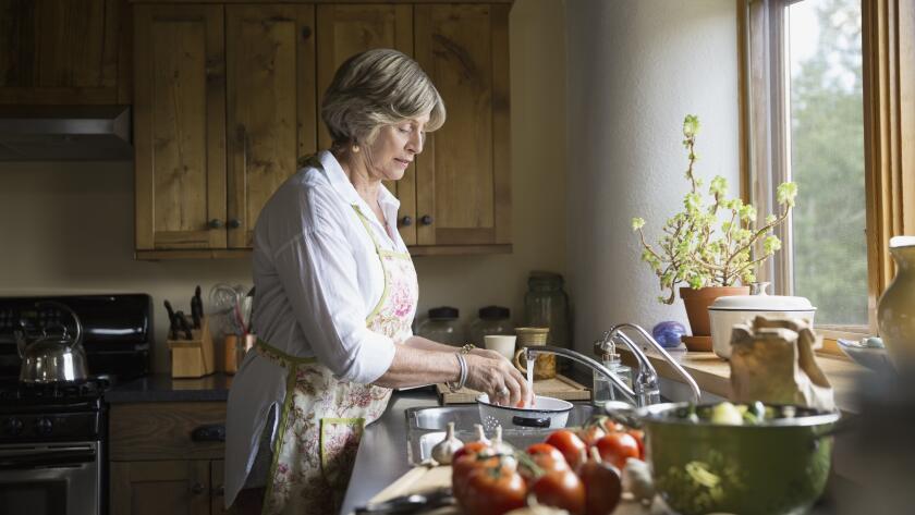 Senior woman washing vegetables at kitchen sink