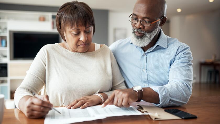 Senior African American couple reviewing paperwork at home