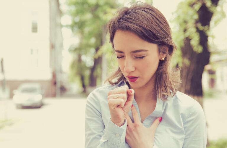 woman coughing into hand