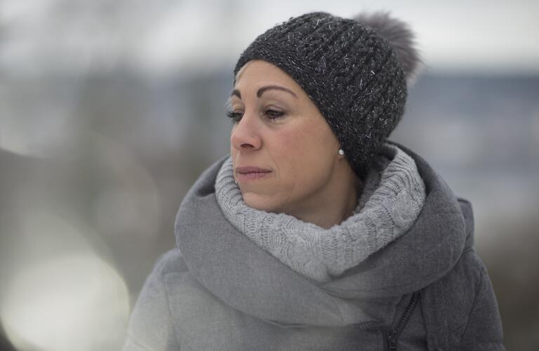 Middle age Caucasian woman in winter coat and hat outside looking sad