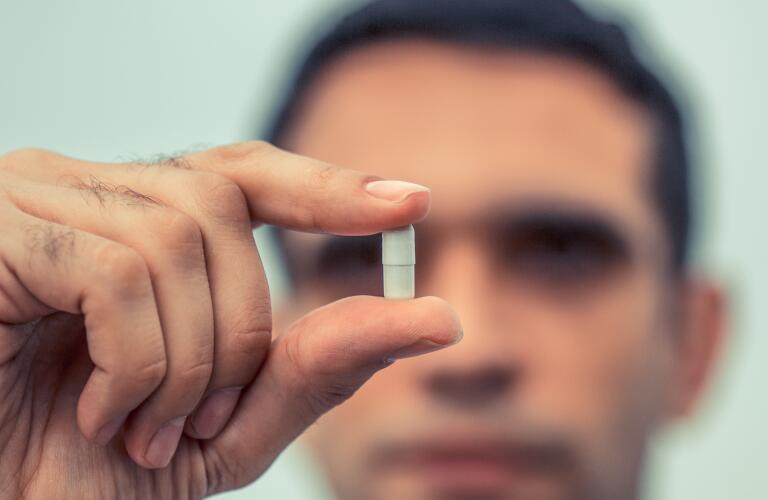 close up of man holding pill
