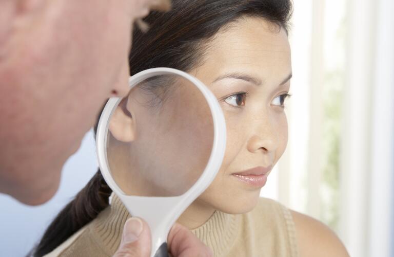 dermatologist-looking-at-patients-skin-with-magnifying-glass