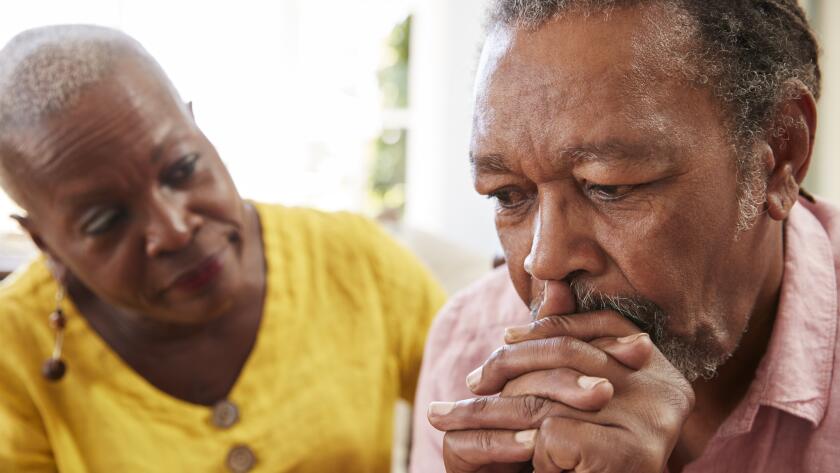 Senior African American man looking concerned while senior African American woman comfort hims