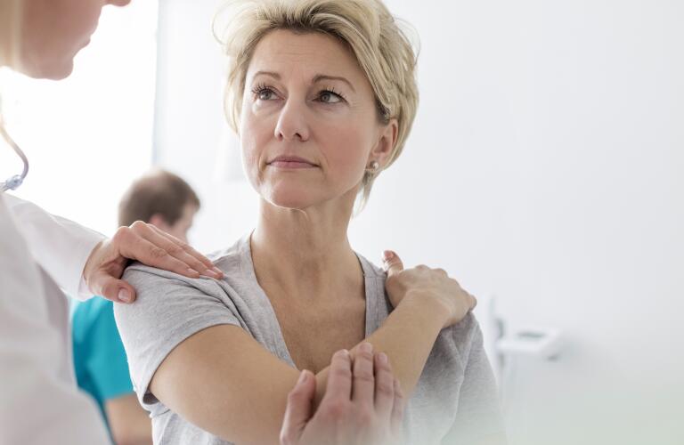 woman-holding-shoulder-at-doctors-appointment