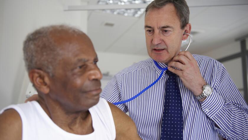 doctor with stethoscope listening to elderly man's breathing