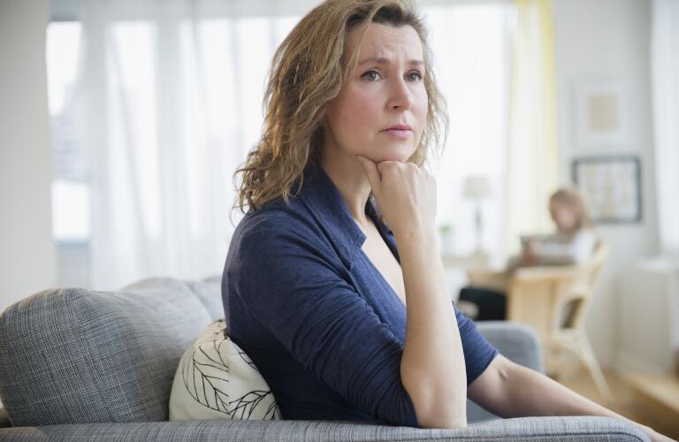 Concerned Caucasian woman sitting on sofa